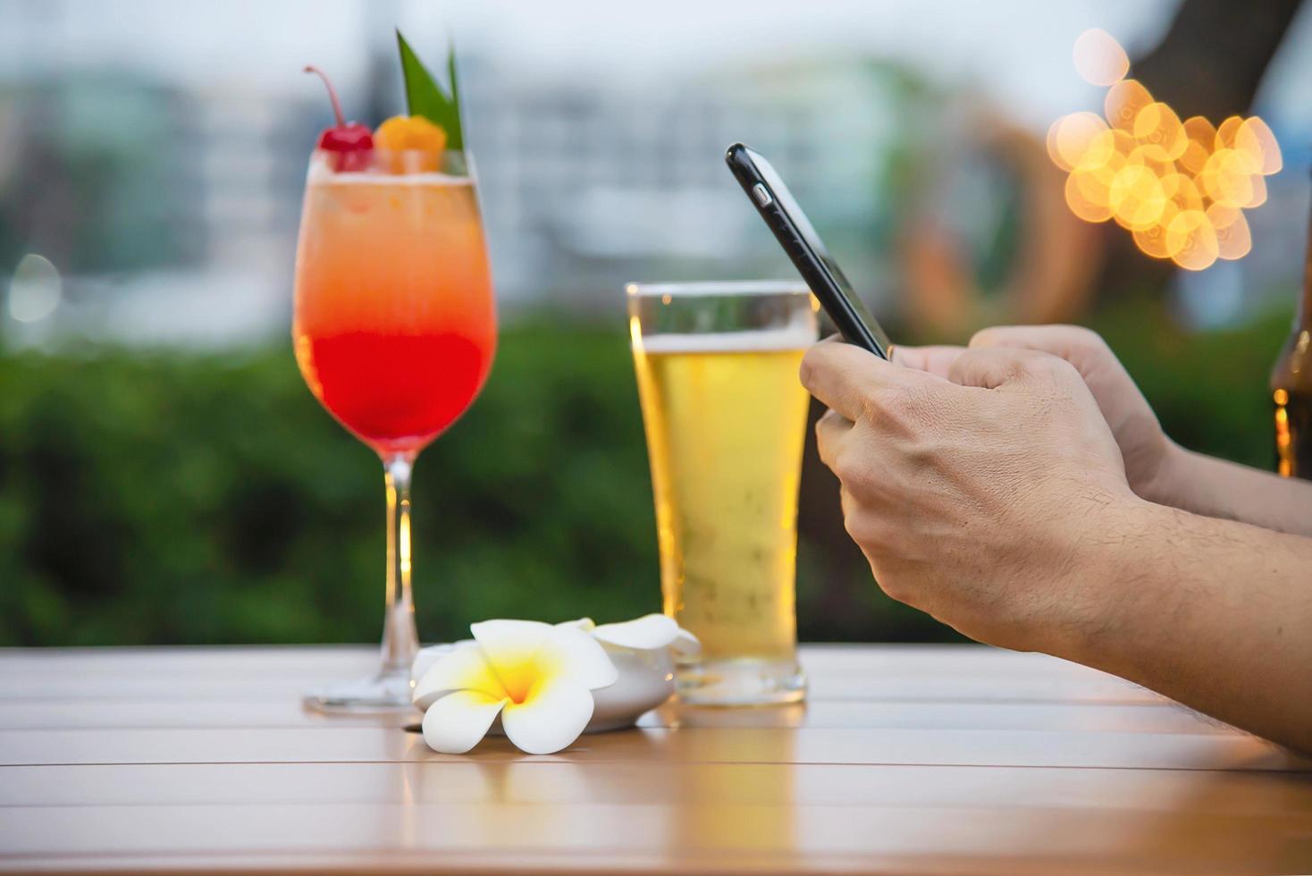 Man using mobile during happy time relax in restaurant with softdrink and green garden background - people relax with technology lifestyle concept photo