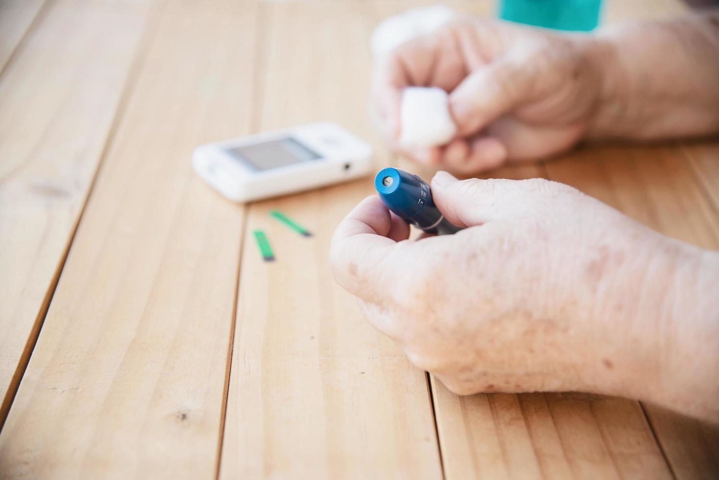 la anciana está probando el nivel de azúcar en la sangre usando el juego de niños de prueba de azúcar en la sangre - personas con concepto de equipo médico foto