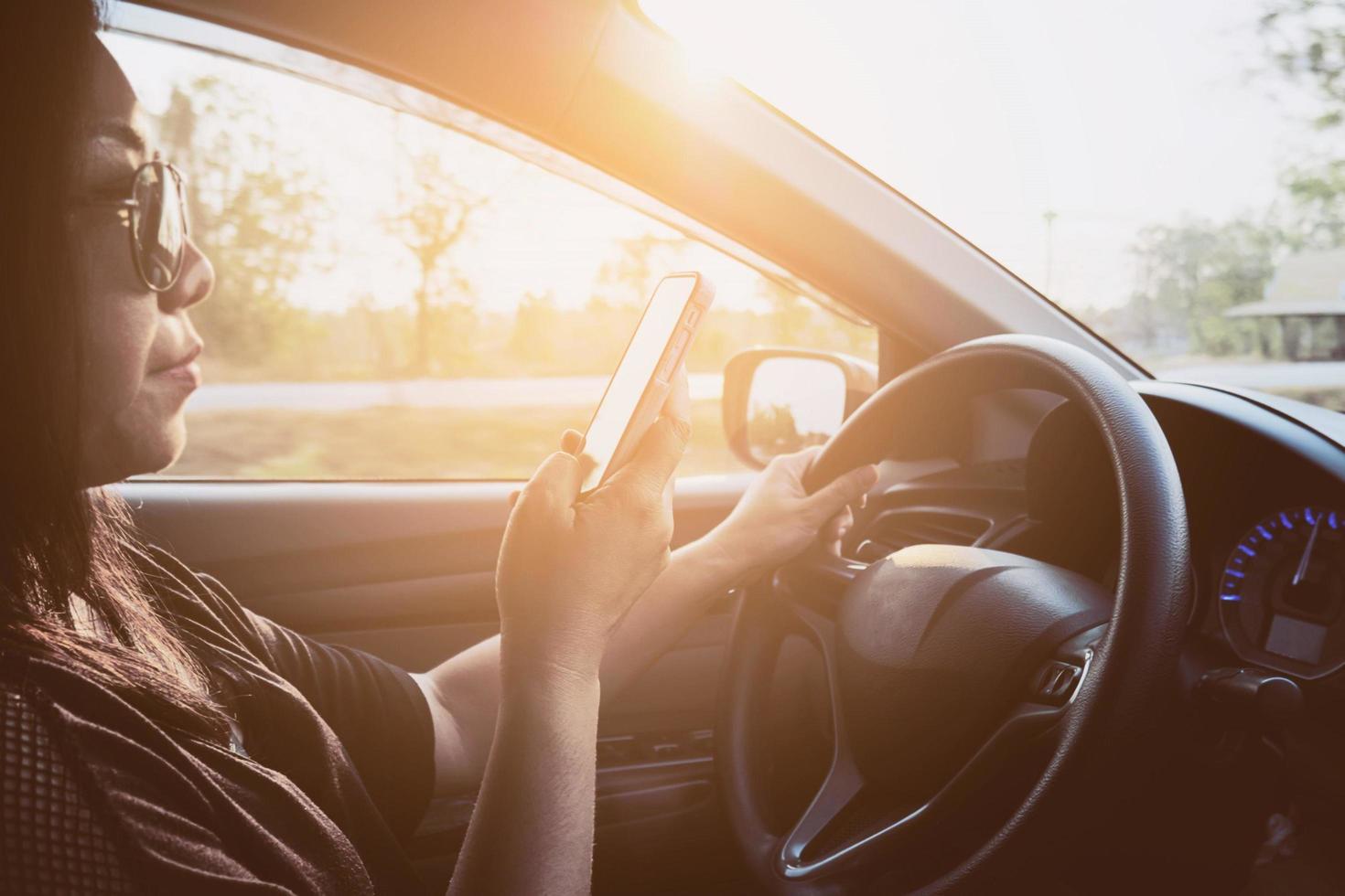 Lady using mobile phone while driving car dangerously photo