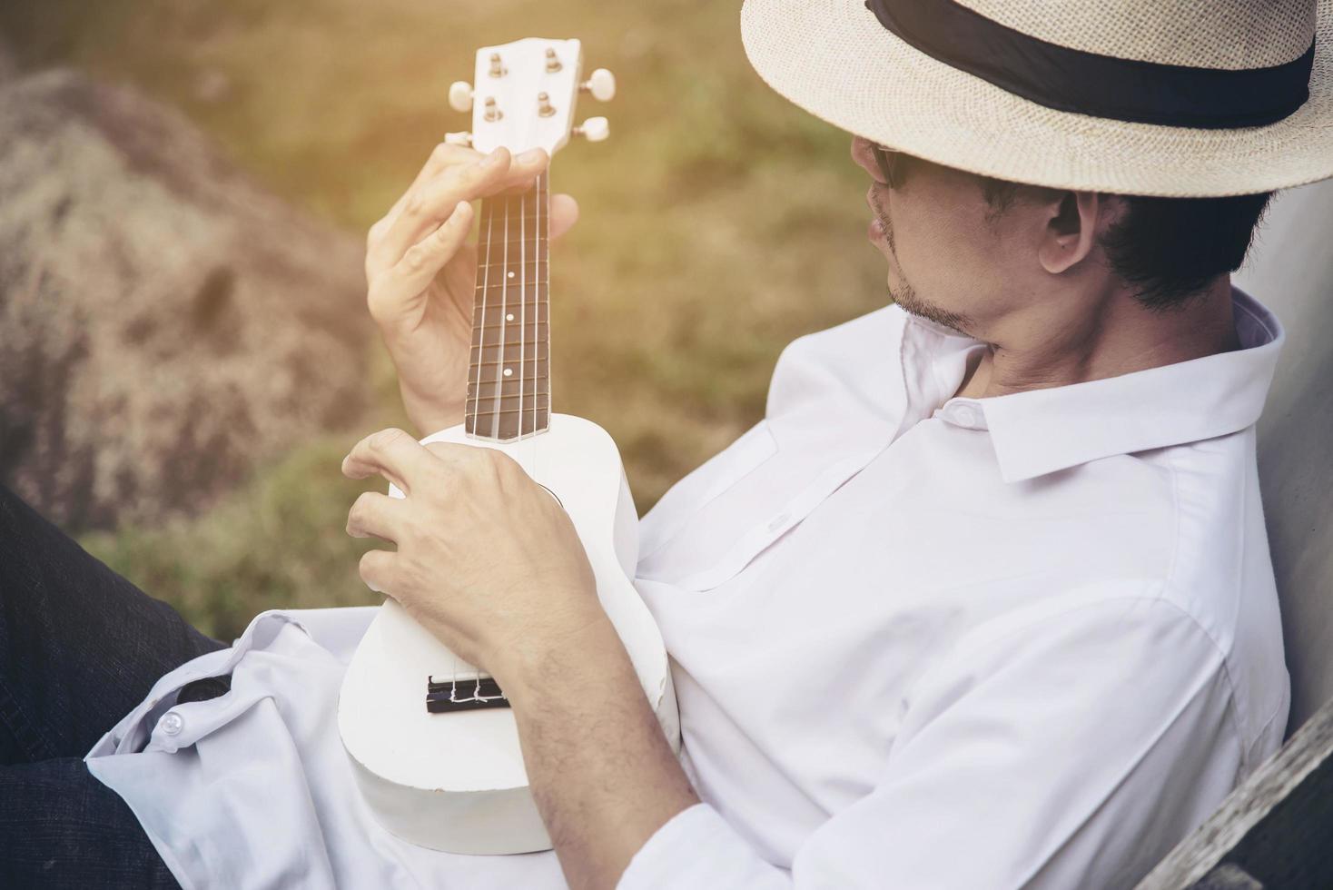 Man play ukulele new to the river- people and music instrument life style in nature concept photo