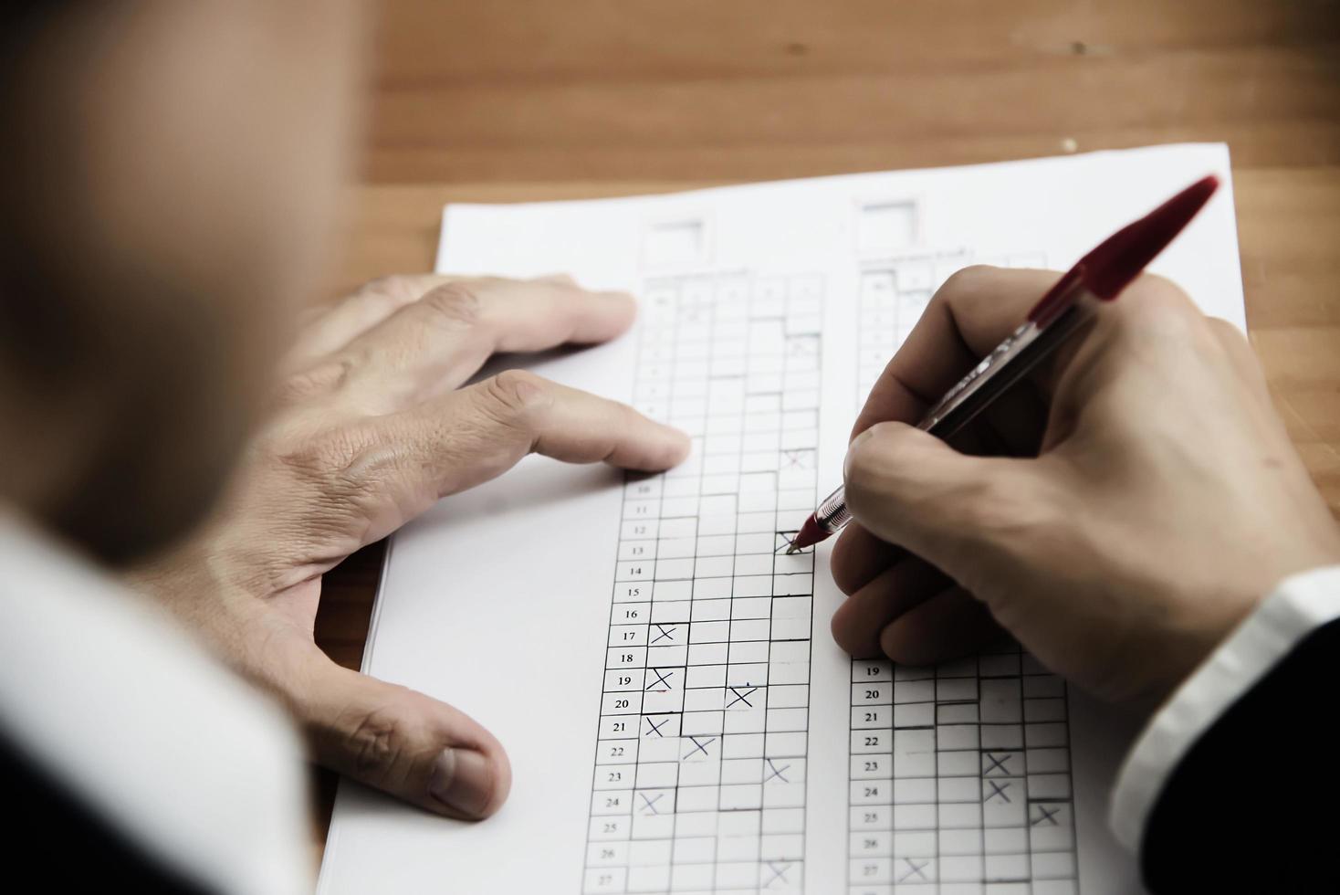 Instructor revisando el examen de la hoja de respuestas de opciones múltiples: personas de educación que trabajan con el concepto de prueba en papel foto