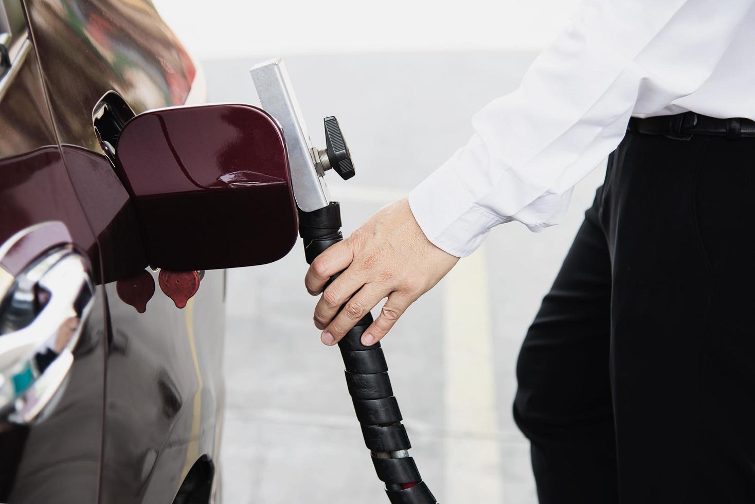 el hombre está poniendo ngv, vehículo de gas natural, dispensador de cabeza a un automóvil en la estación de gasolina en tailandia foto