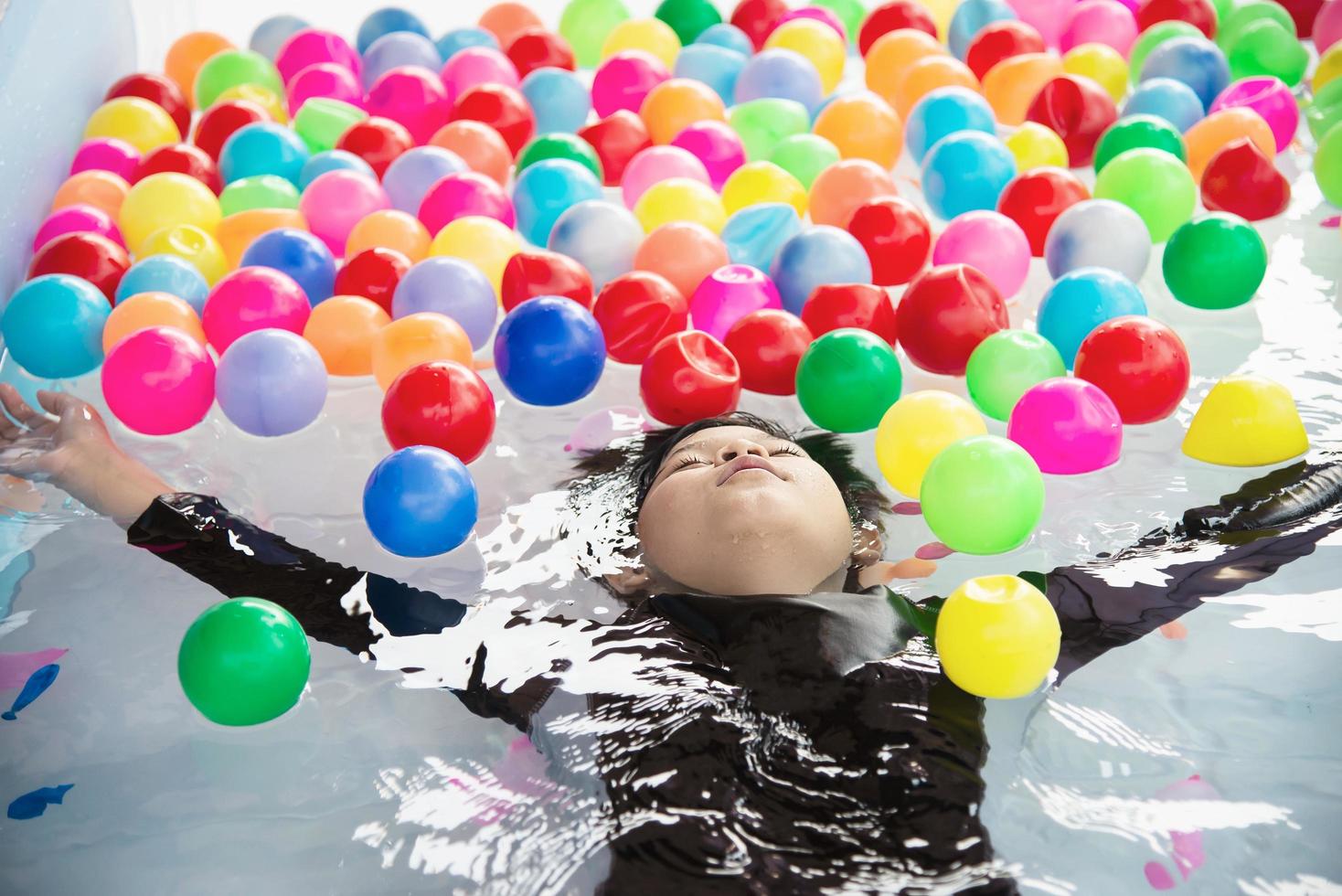 Boy playing with colourful ball in small swimming pool toy - happy boy in water pool toy concept photo
