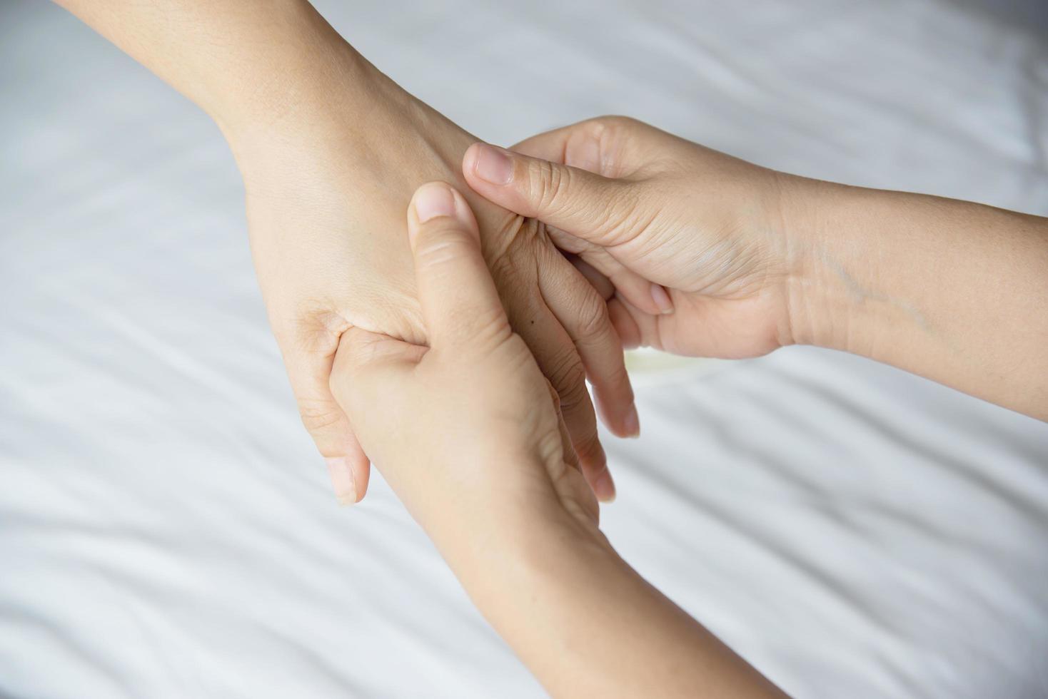 masaje de spa de manos sobre fondo de cama blanca y limpia - la gente se relaja con el servicio de masaje de manos foto