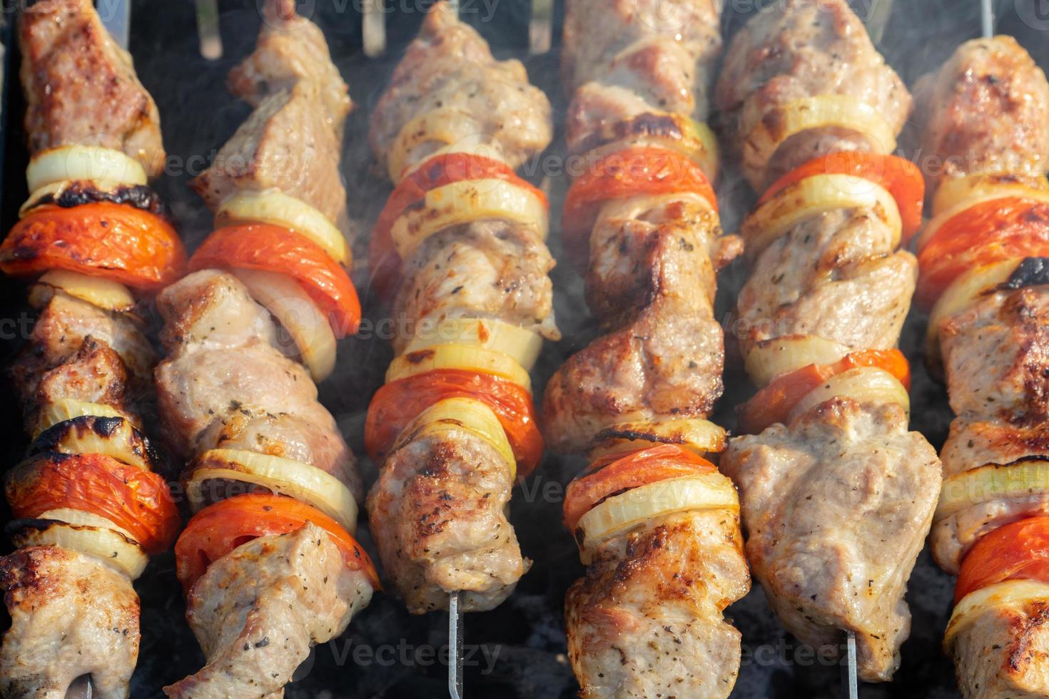 Marinated barbecue meat on skewer. Shish kebab or Shashlyk meaning skewered  meat. Beef or pork on grill on an open fire with smoke. Street food, picnic  concept Stock Photo