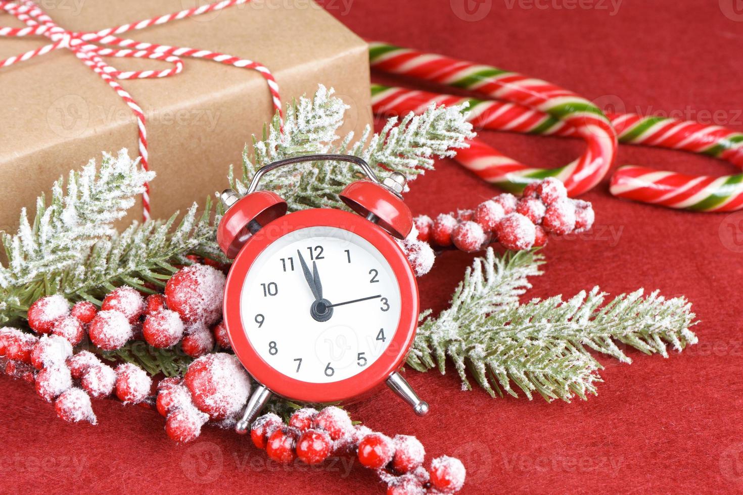 Christmas snow fir tree, alarm clock and gift box on red background. photo