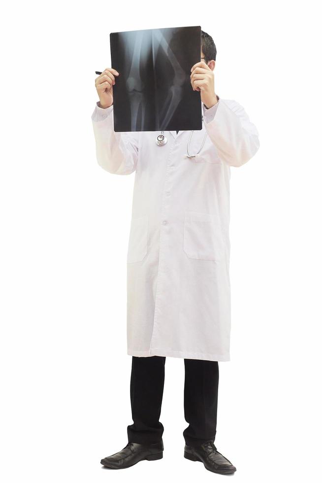 médico varón de pie examinar la película de rayos x aislado sobre blanco foto
