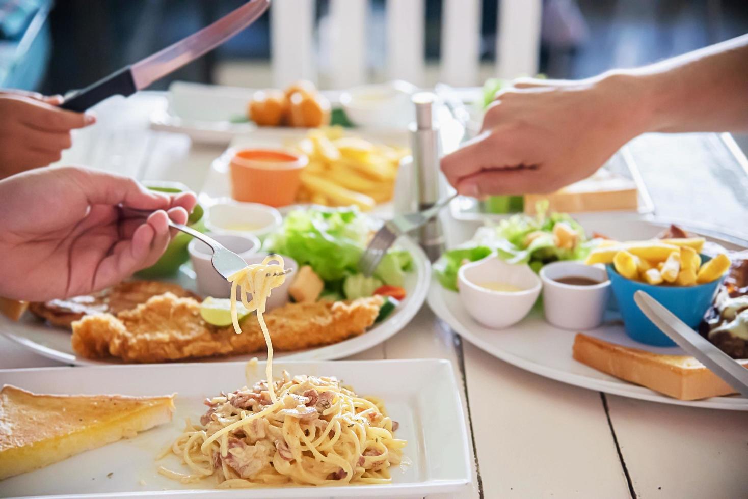 People enjoy eat spaghetti and steak together in a big meal set - family happy time with food concept photo