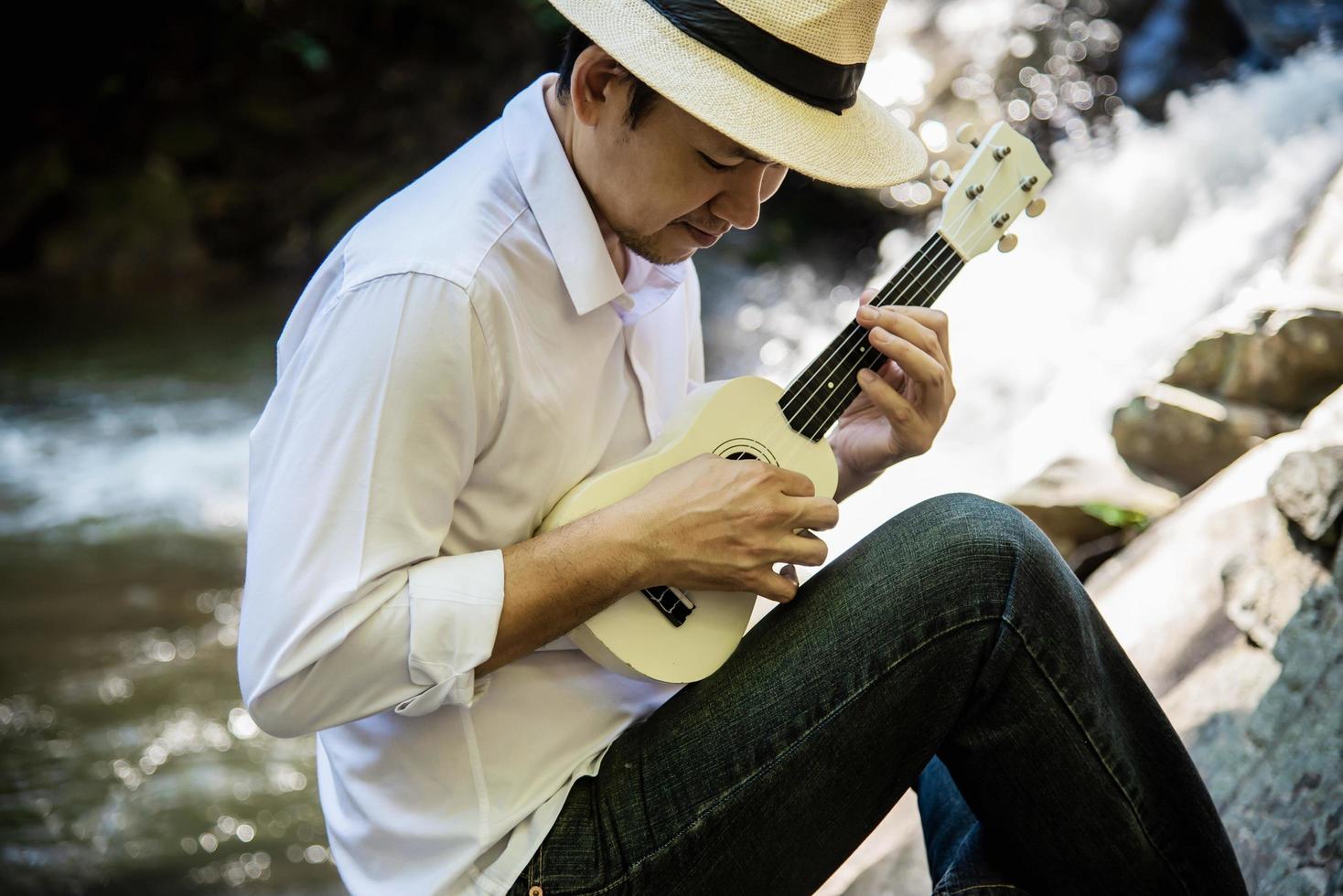 el hombre toca el ukelele nuevo en la cascada - la gente y el estilo de vida del instrumento musical en el concepto de naturaleza foto