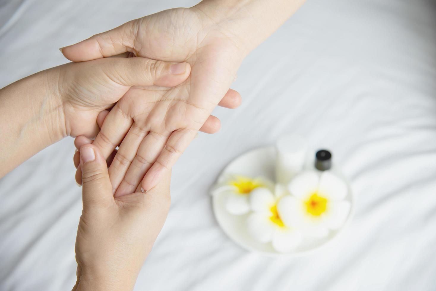 masaje de spa de manos sobre fondo de cama blanca y limpia - la gente se relaja con el servicio de masaje de manos foto
