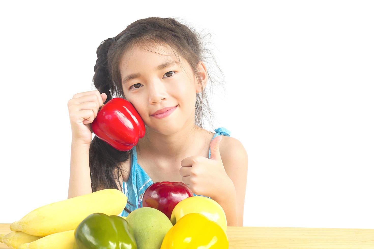 Gril asiático saludable mostrando expresión feliz con variedad de frutas y verduras de colores sobre fondo blanco. foto