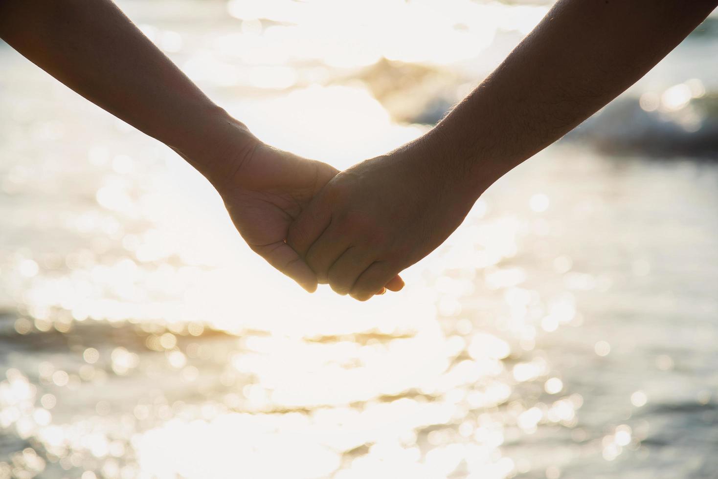 Asian couple is holding hand near to the sea photo