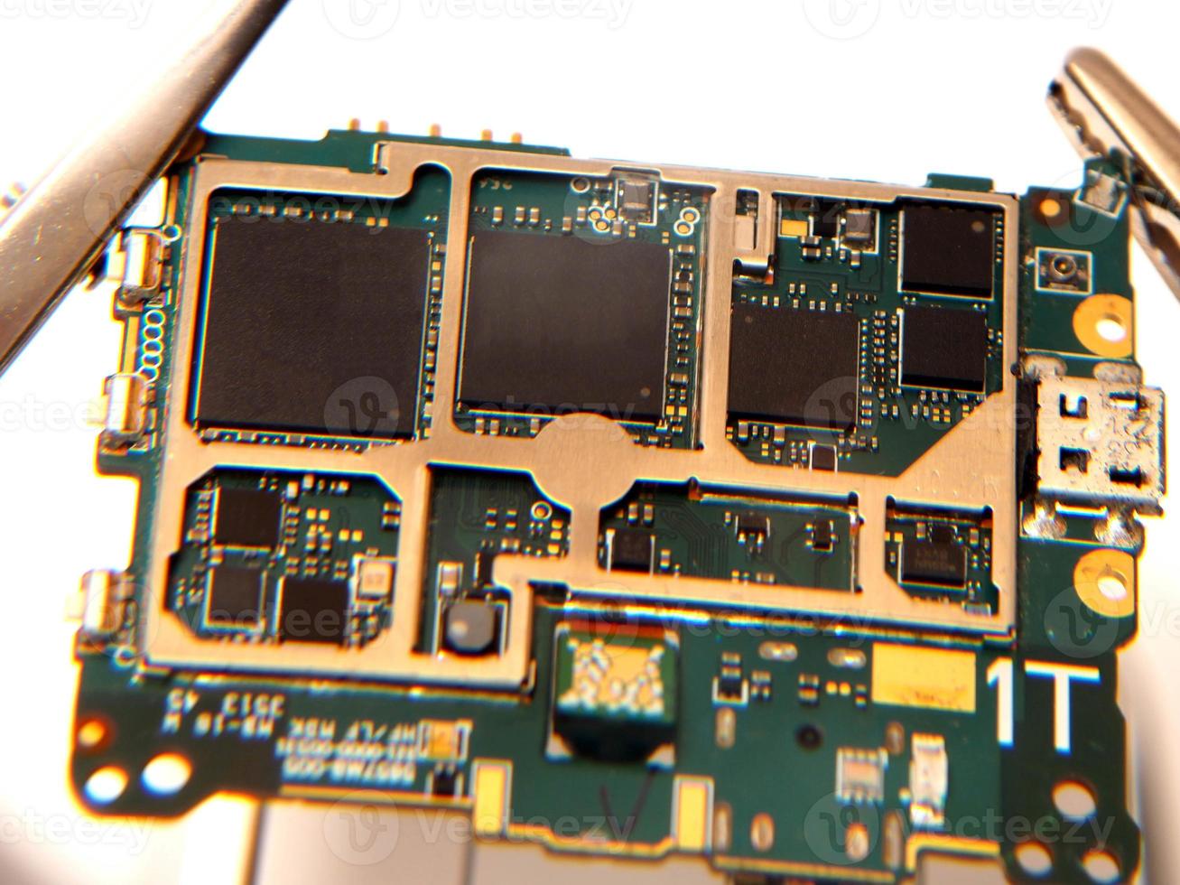 Close up shoot of printed circuit board PCB sitting on a white repair stand with magnifier for better examining small parts photo