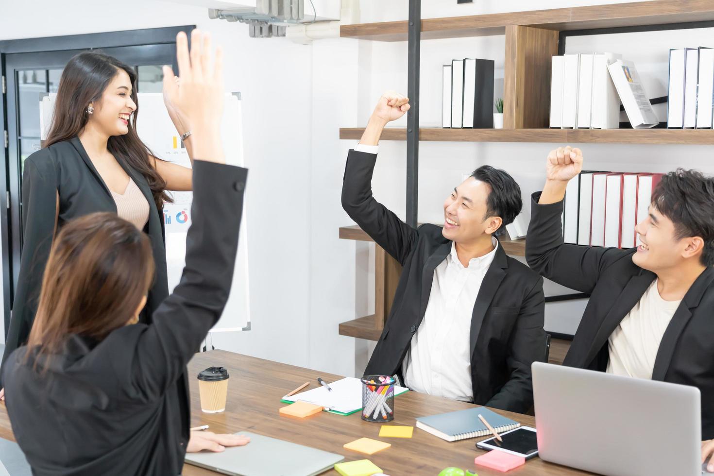 gente de negocios feliz en la computadora celebrando el éxito en el trabajo sentado en la oficina moderna. negociaciones exitosas. equipo de negocios mirando el monitor de la computadora. foto