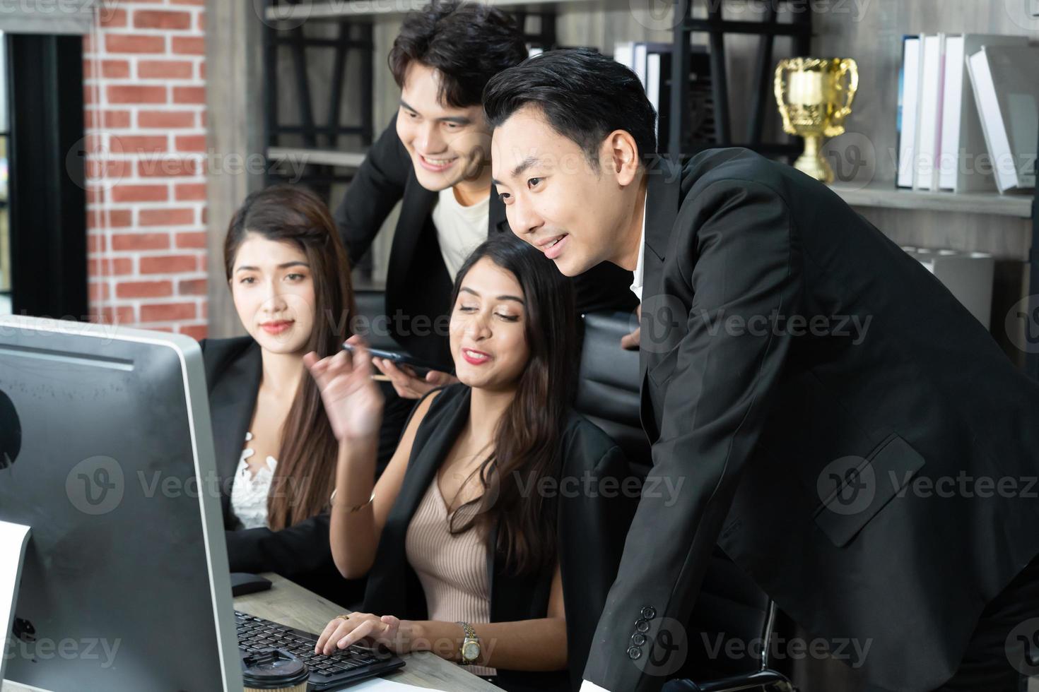 successful business multiage team standing around computer for presentation of work. Group of business people in a meeting at office, working on computer photo