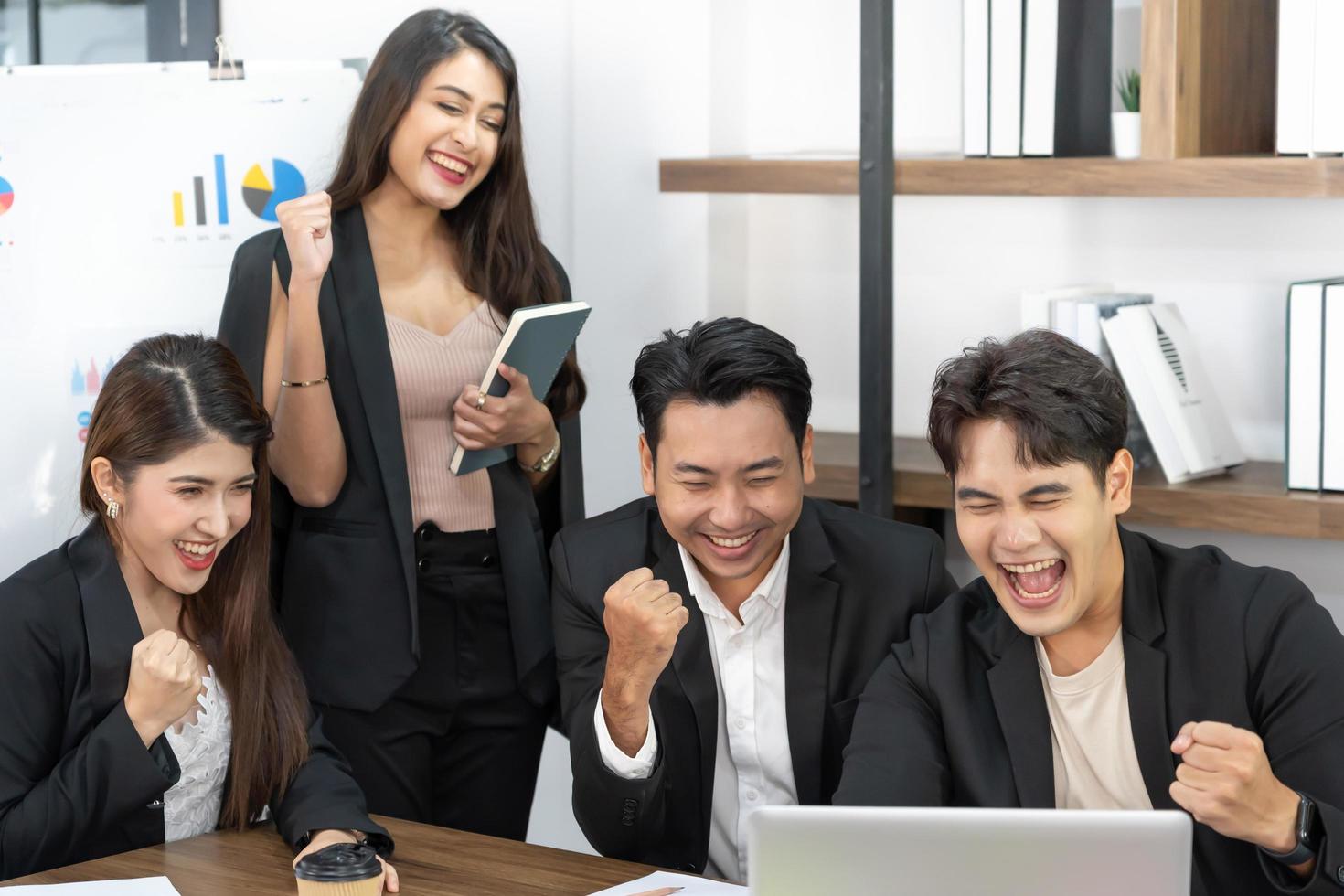 gente de negocios feliz en la computadora celebrando el éxito en el trabajo sentado en la oficina moderna. negociaciones exitosas. equipo de negocios mirando el monitor de la computadora. foto