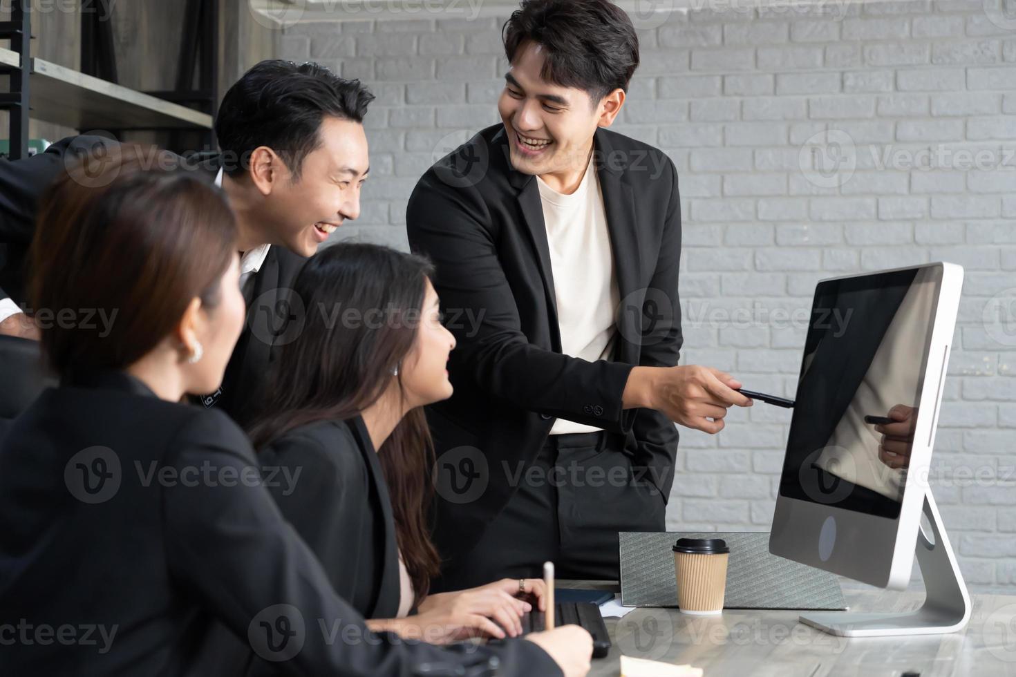 exitoso equipo empresarial multiedad de pie alrededor de la computadora para la presentación del trabajo. grupo de empresarios en una reunión en la oficina, trabajando en la computadora foto