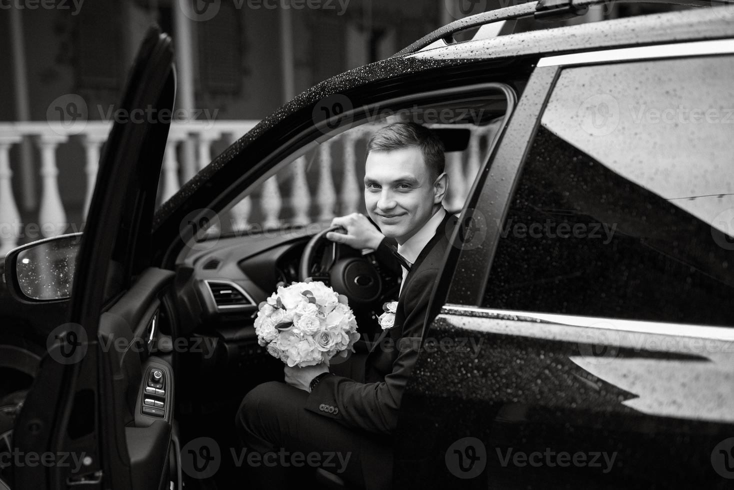 portrait of a young guy groom in a black suit photo