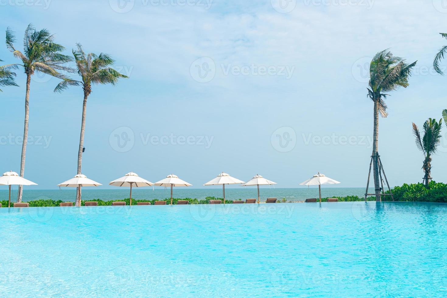 umbrella with bed pool around swimming pool with ocean sea background photo