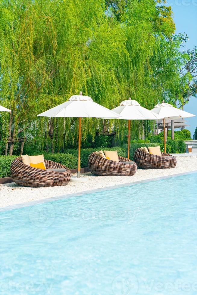 outdoor patio chair with pillow and umbrella around swimming pool photo