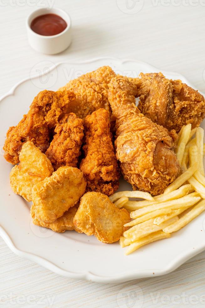 pollo frito con papas fritas y nuggets en un plato foto