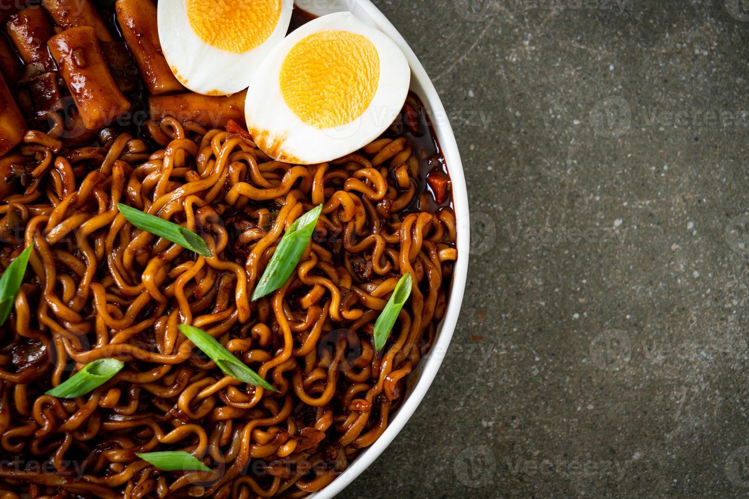 jjajang rabokki - fideos instantáneos coreanos o ramyeon con pastel de arroz coreano o tteokbokki y huevo en salsa de frijoles negros foto