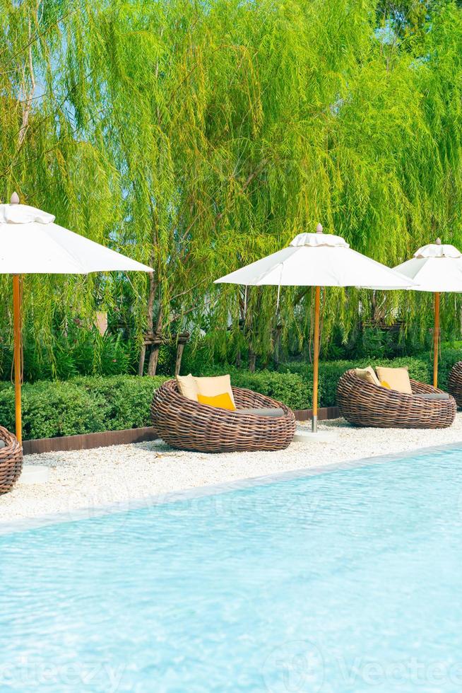 outdoor patio chair with pillow and umbrella around swimming pool photo