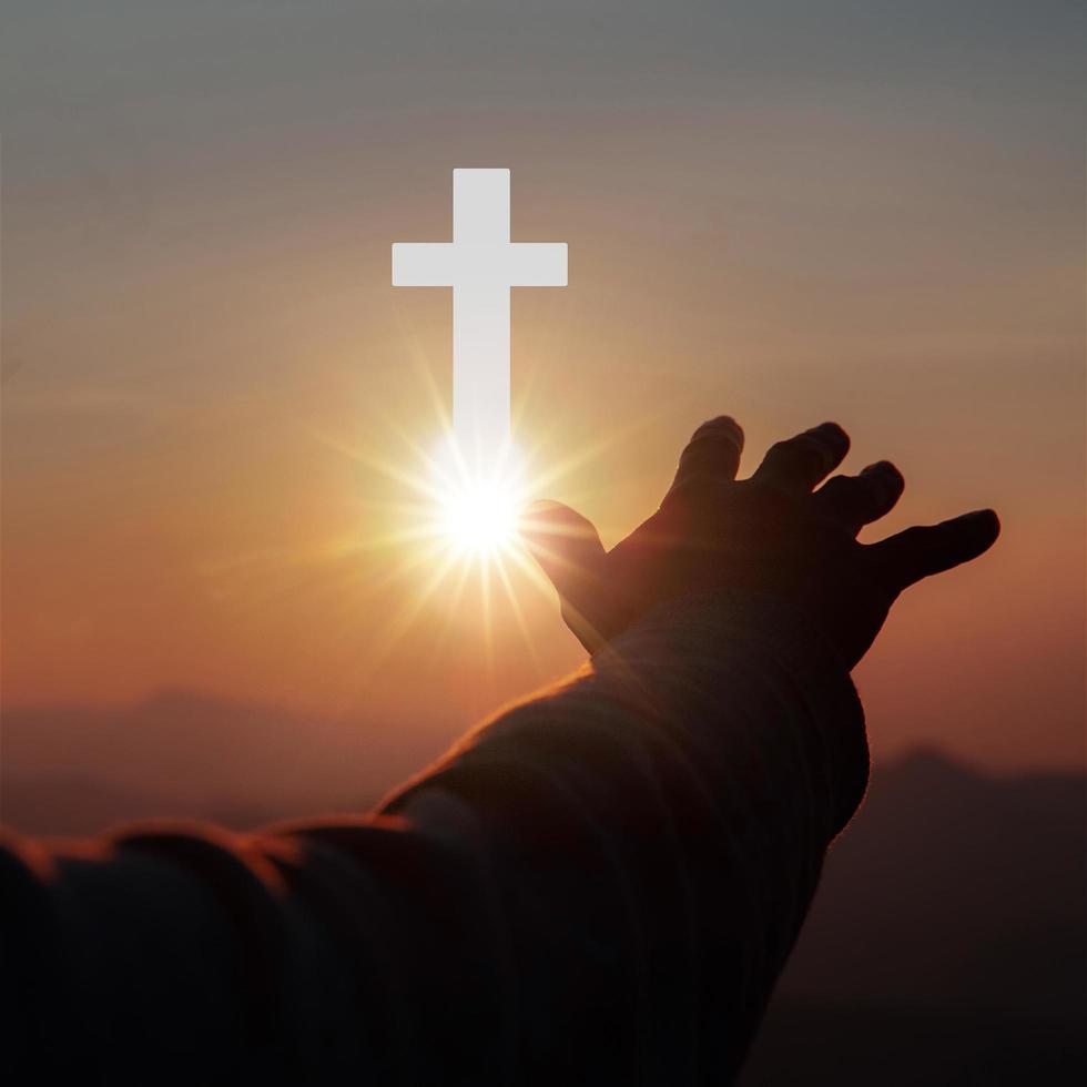 Silhouette of human hands palm up praying and worship of cross, eucharist therapy bless god helping, belief, forgiveness, freedom, hope and faith, christian religion concept on sunset background. photo