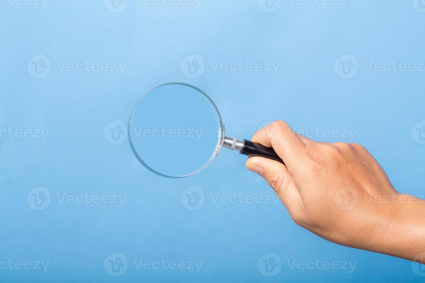 mujer mano sosteniendo lupa aislado sobre fondo azul. la lente de zoom óptico es una herramienta macro, concepto para la educación, la ciencia. foto