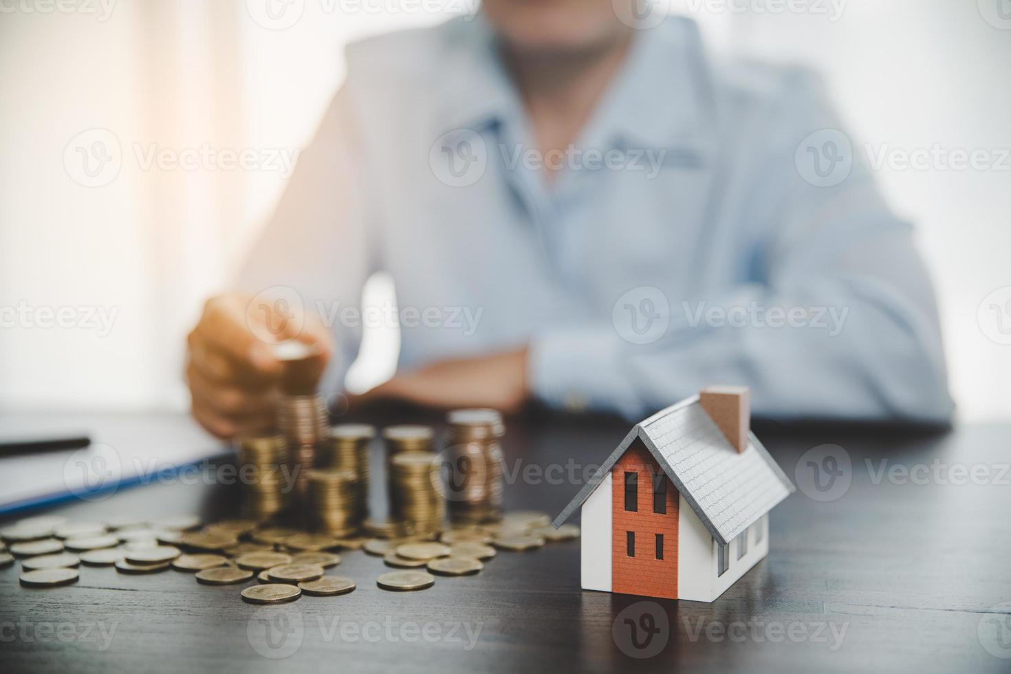 modelo de casa con monedas apiladas, la mano de negocios está planeando ahorrar dinero en monedas para comprar una casa. concepto de escalera de propiedad, hipoteca con inversión inmobiliaria y ahorro o inversión para una casa foto