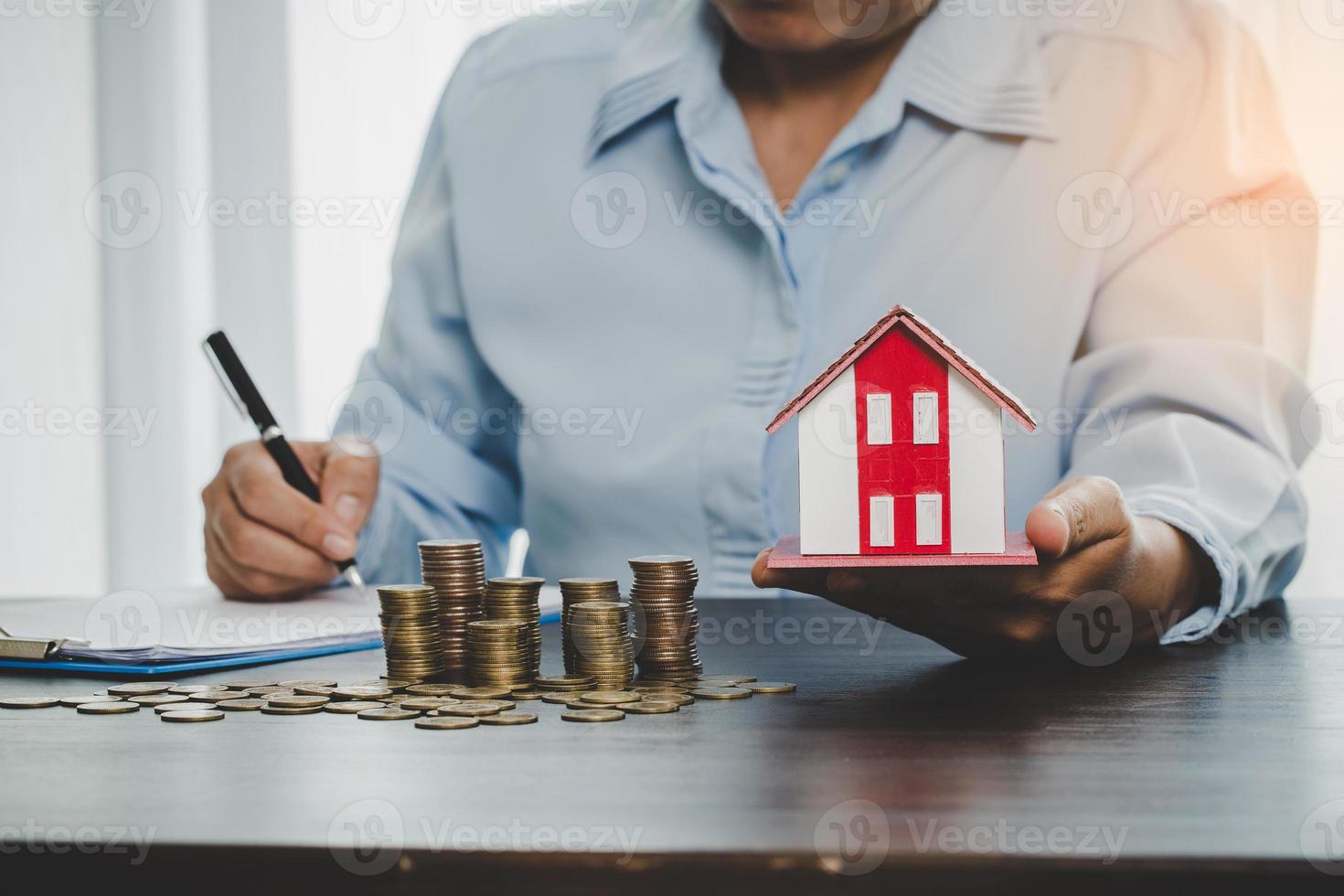 modelo de casa con monedas apiladas, la mano de negocios está planeando ahorrar dinero en monedas para comprar una casa. concepto de escalera de propiedad, hipoteca con inversión inmobiliaria y ahorro o inversión para una casa foto