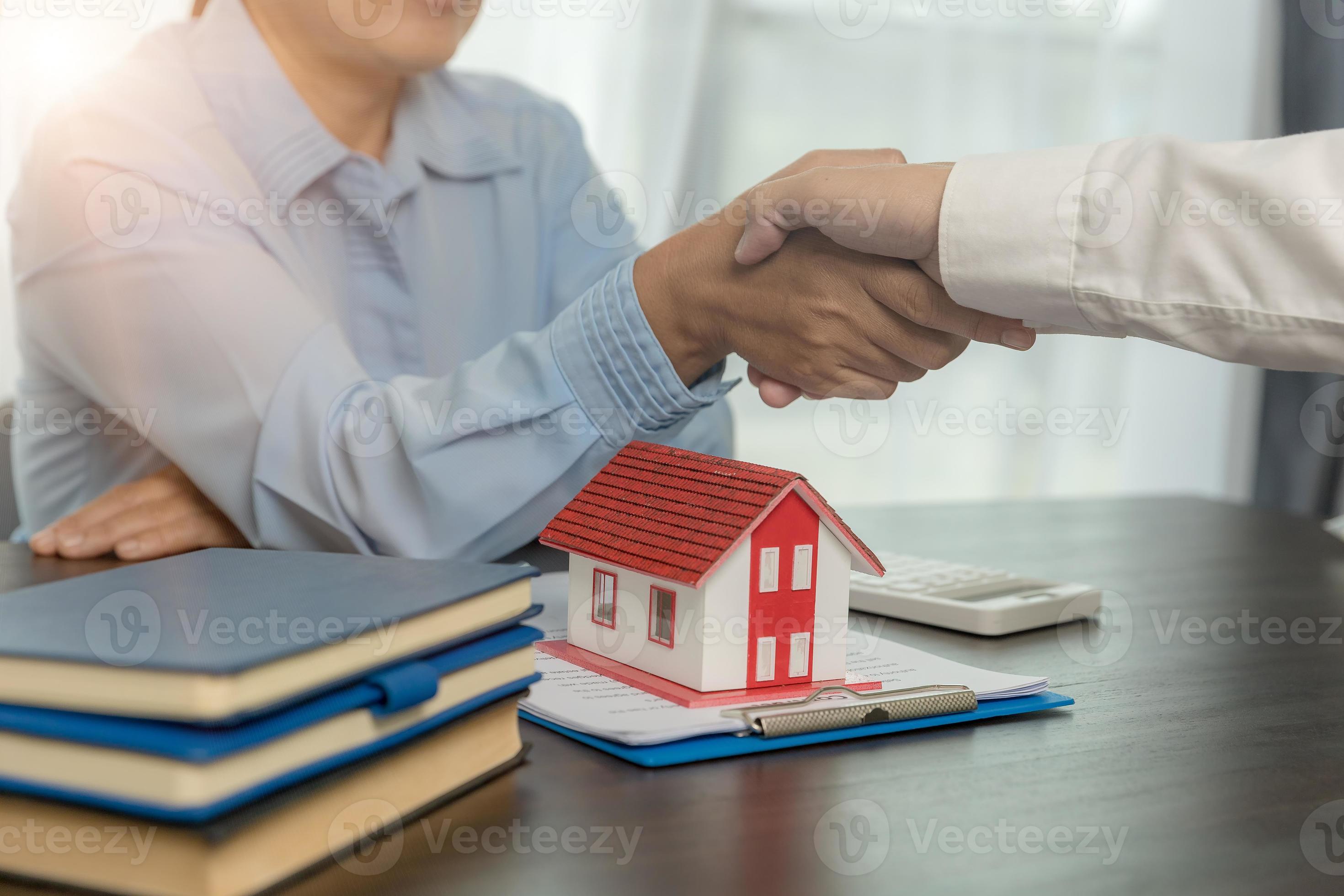 Estate agent shaking hands with client after contract signature and