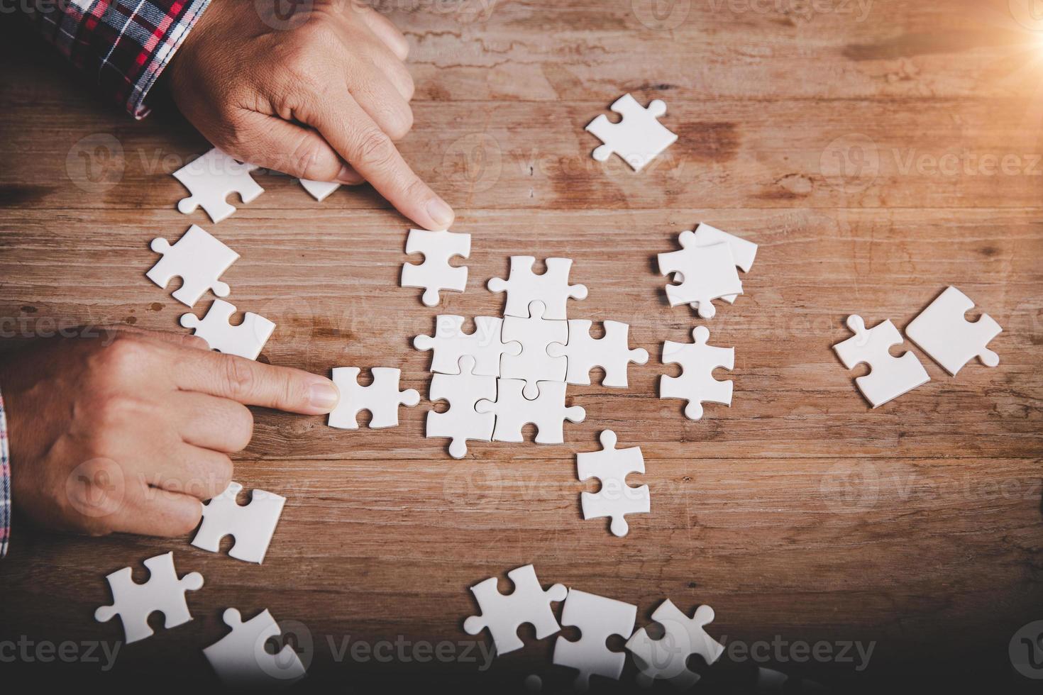 Hands holding jigsaw puzzles piece on wooden table background, success business, solution strategy, teamwork partnership concept photo