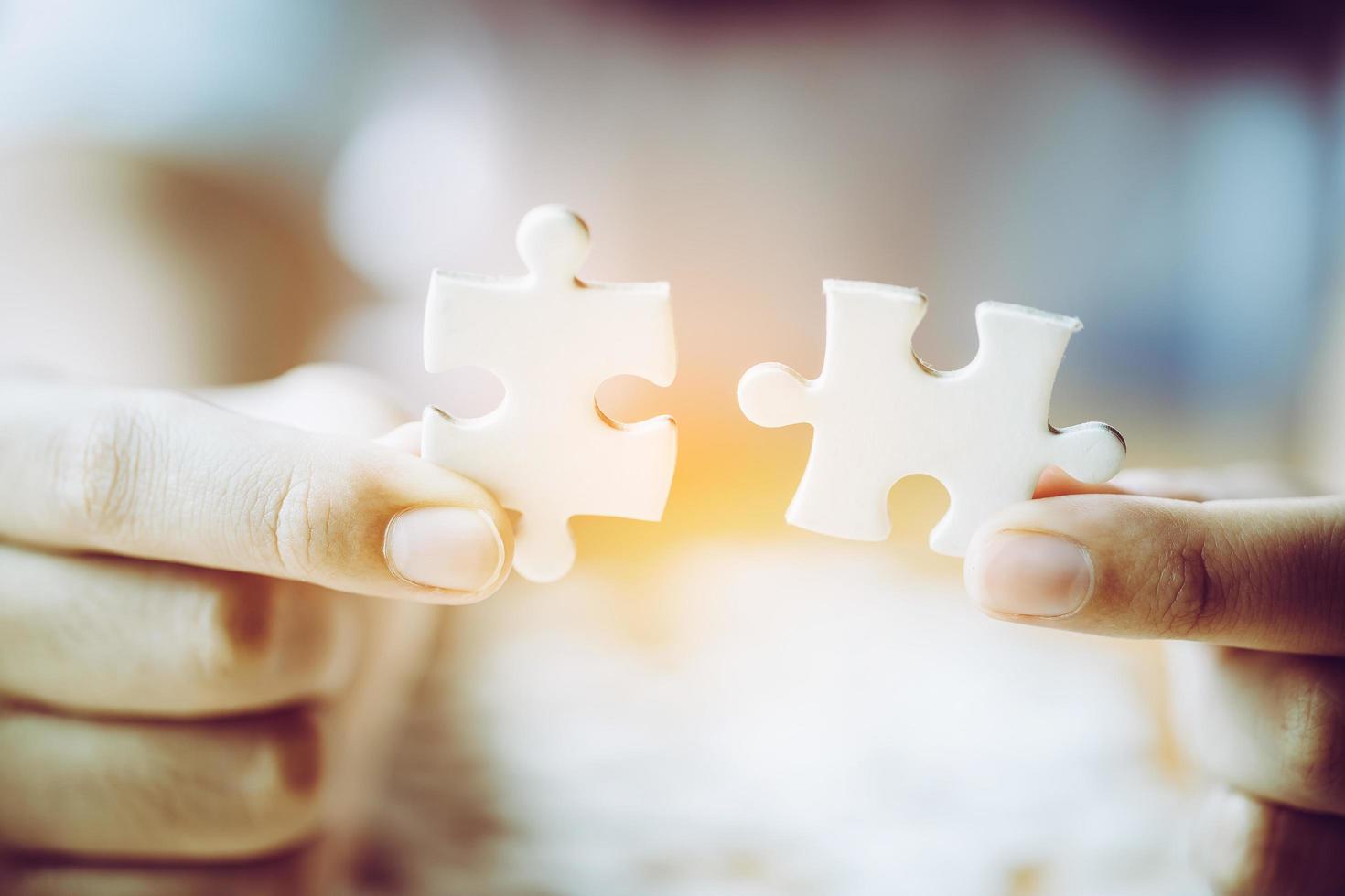 Hands of a person little child and parent playing jigsaw puzzle piece game together on wooden table at home, concept for leisure with family, play with children's development, education and fun. photo