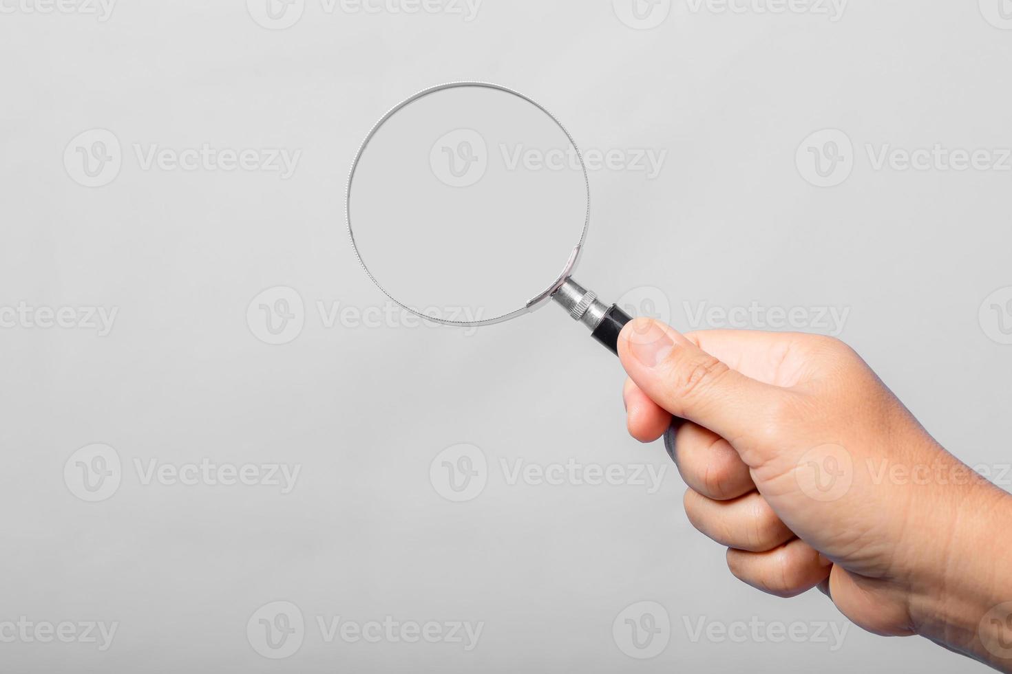 woman hand holding magnifying glass isolated on gray background. optical zoom lens is macro tool, concept for education, science. photo