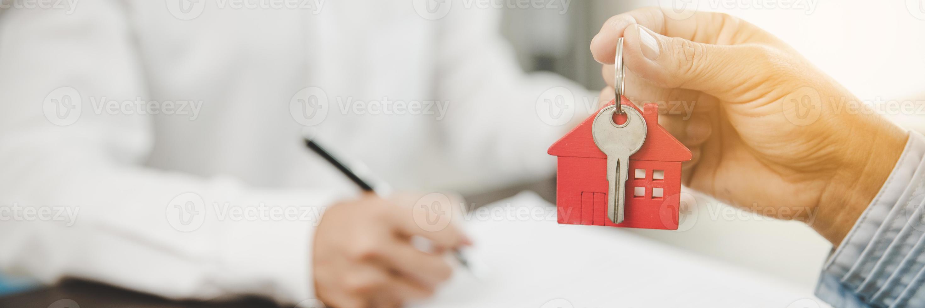 real estate agent holding house key to his client after signing contract, concept for business loan, investment mortgage, real estate, moving home or renting property. banner with copy space photo