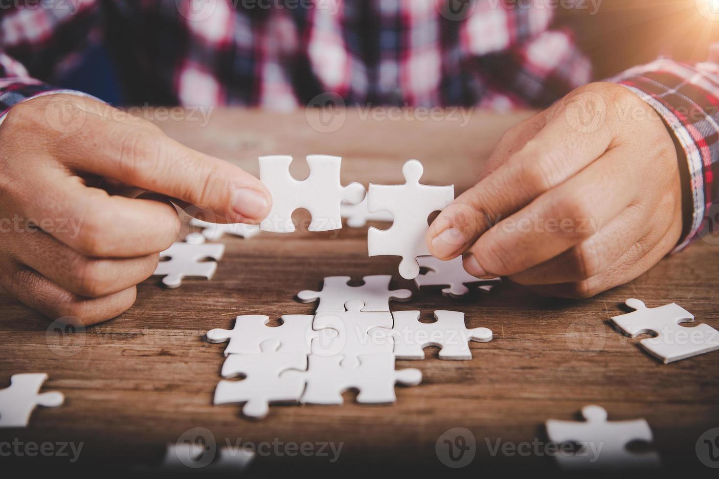Hands holding jigsaw puzzles piece on wooden table background, success business, solution strategy, teamwork partnership concept photo