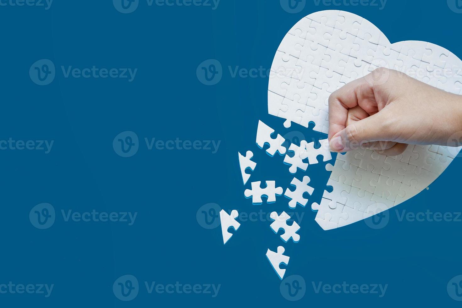 Close up hand holding and playing jigsaw game incomplete. White part of jigsaw puzzle pieces on blue background. concepts of problem solving, business, teamwork, Texture photo with copy space for text