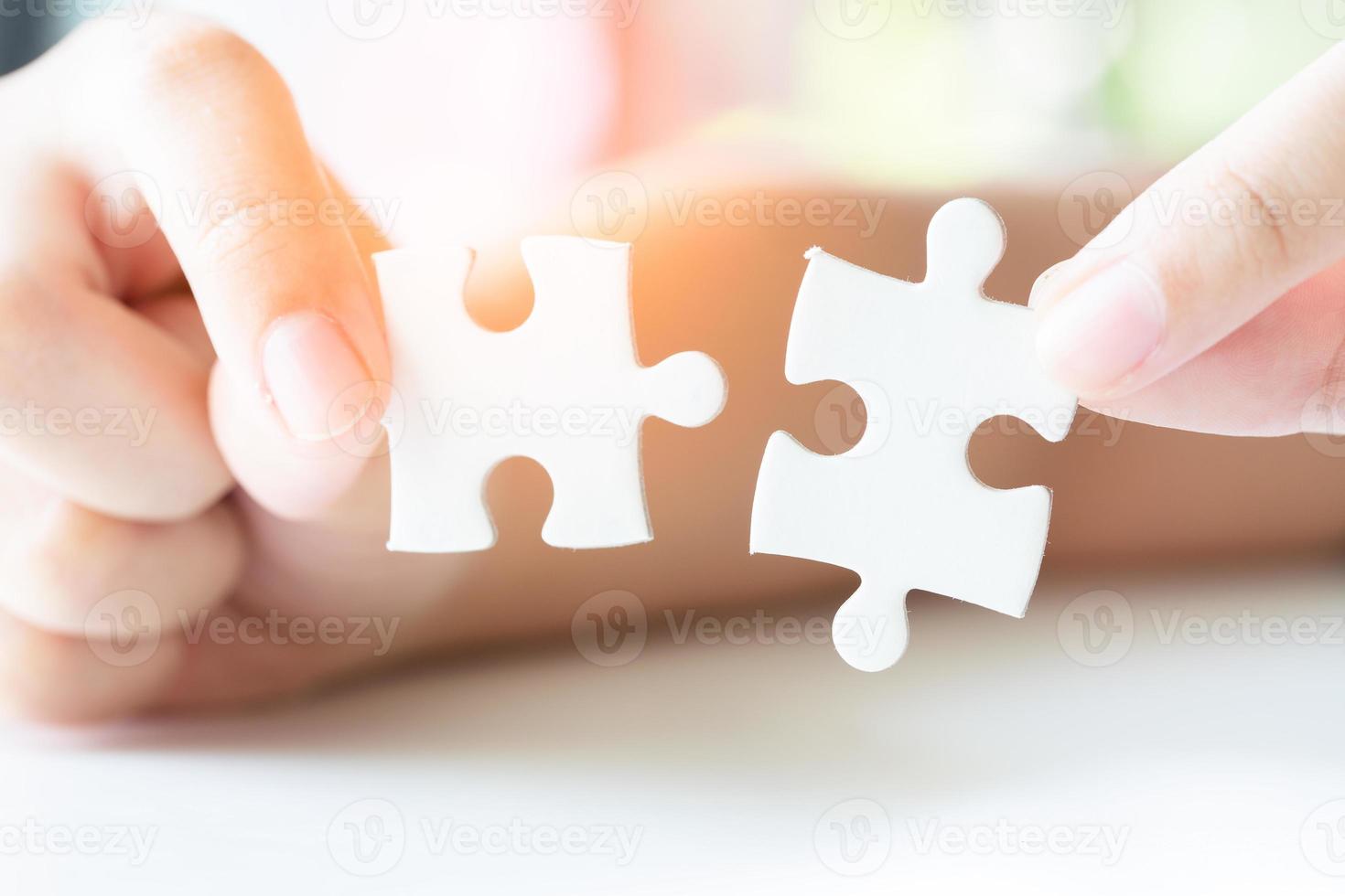 Close up hand holding and playing jigsaw game incomplete. White part of jigsaw puzzle pieces. concepts of problem solving, business, teamwork. photo