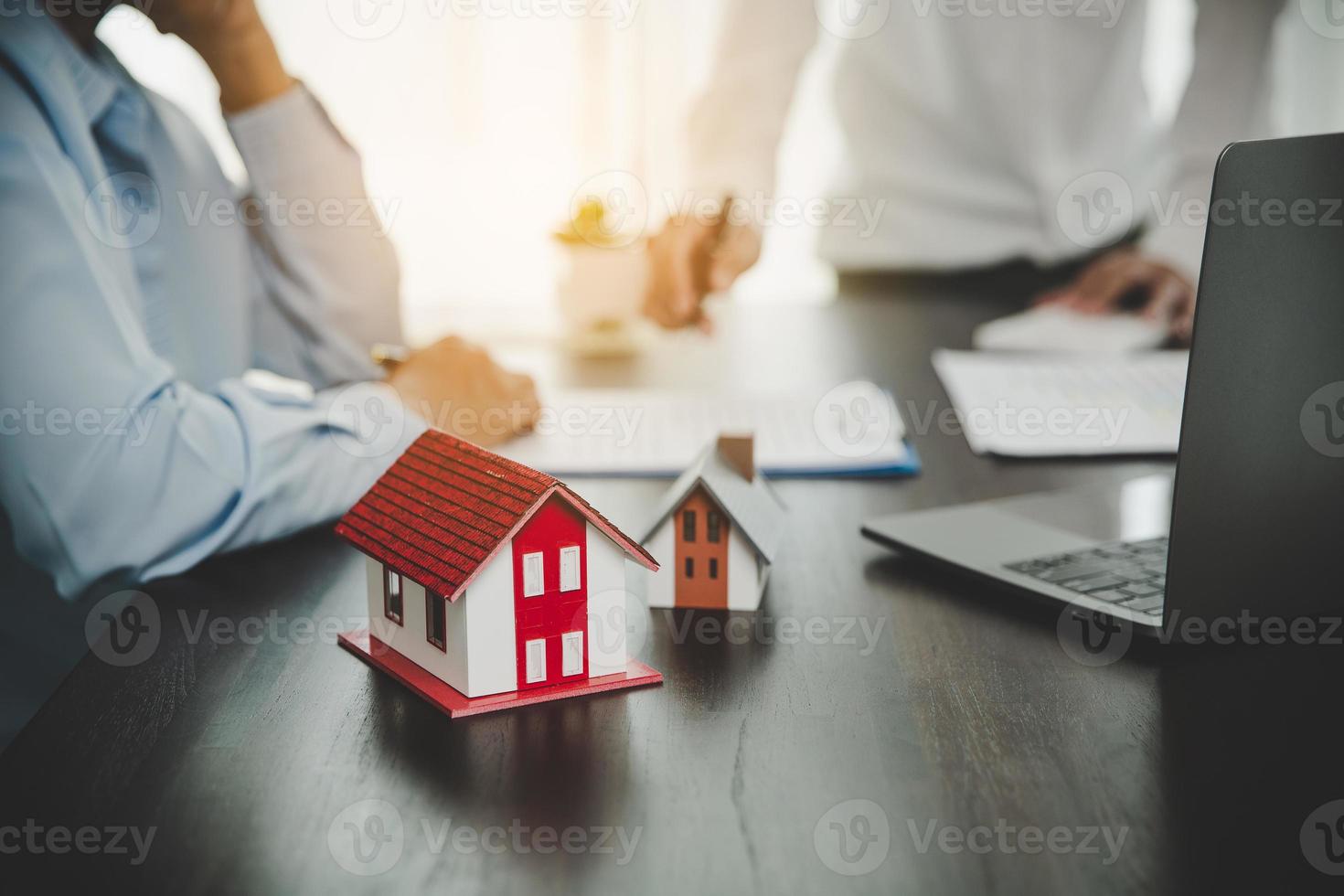Real estate broker agent presenting and consult to customer to decision making sign insurance form agreement, home model, concerning mortgage loan offer for and house insurance. photo