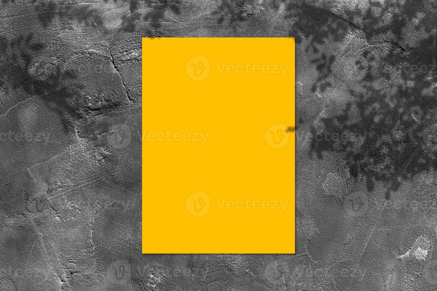 Empty yellow square poster mockup with light shadow on black concrete wall background. photo