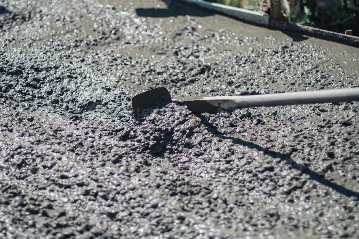 A construction worker pouring a wet concret at road construction site photo