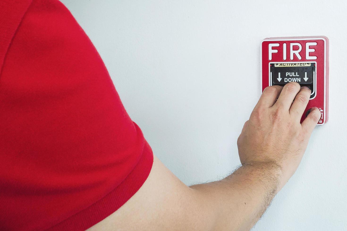 Man is reaching his hand to push fire alarm hand station photo