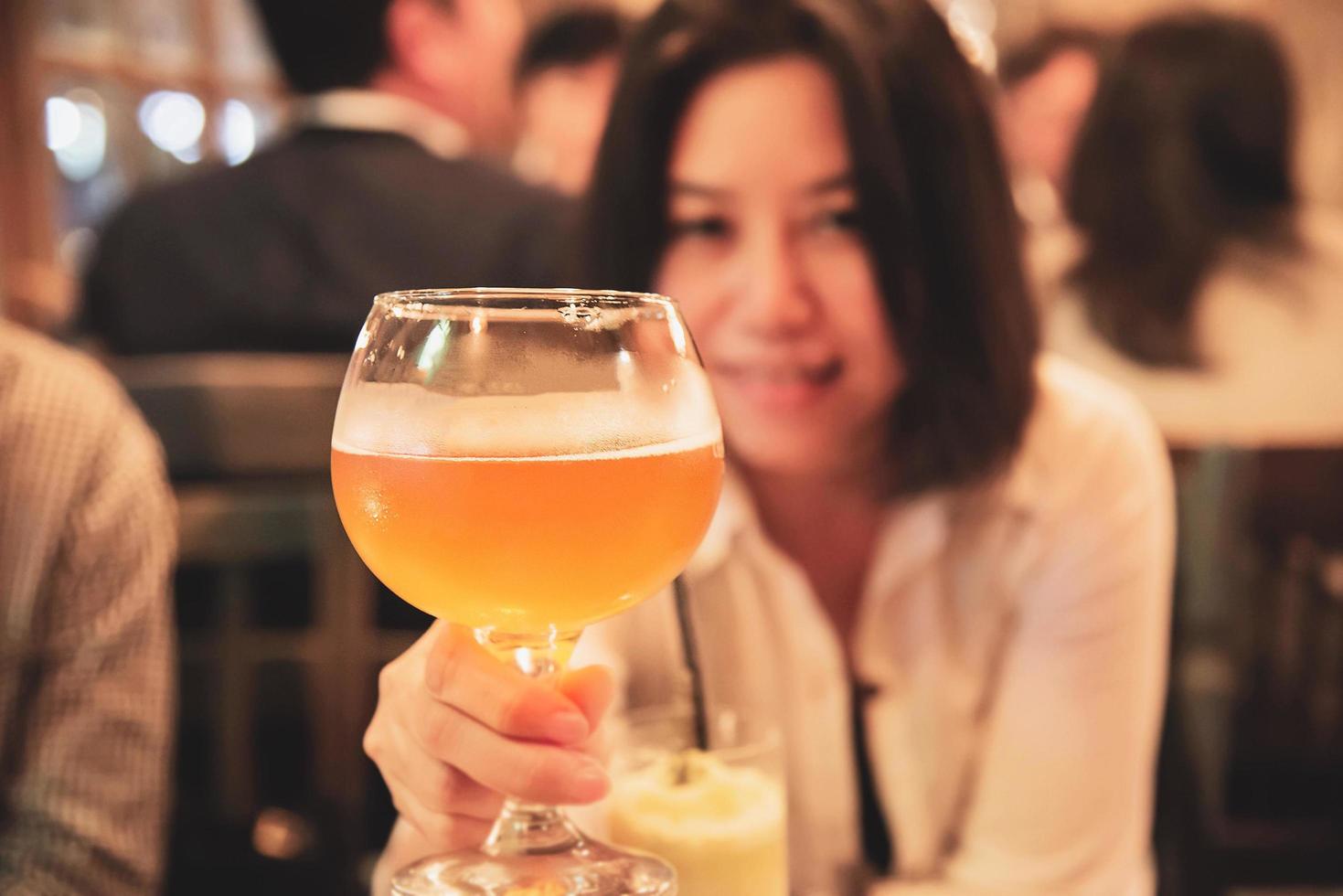 Happy lady shows a big glass of beer in restaurant - celebration beer cheers concept photo