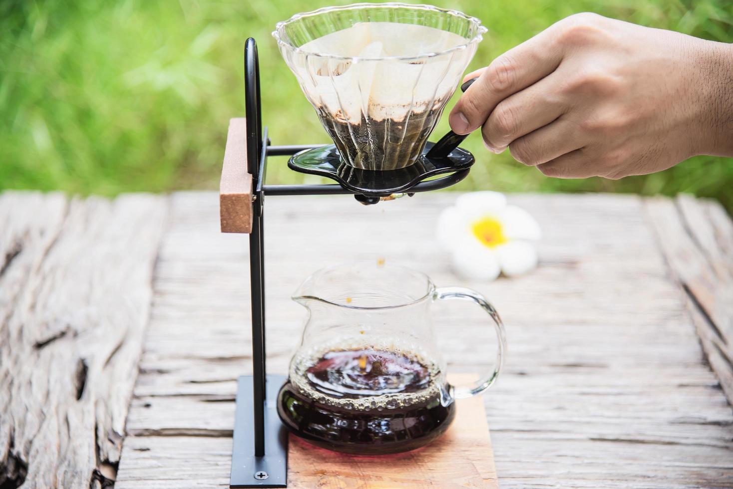 Man making drip fresh coffee in vintage coffee shop with green nature background - people with fresh coffee in nature concept photo