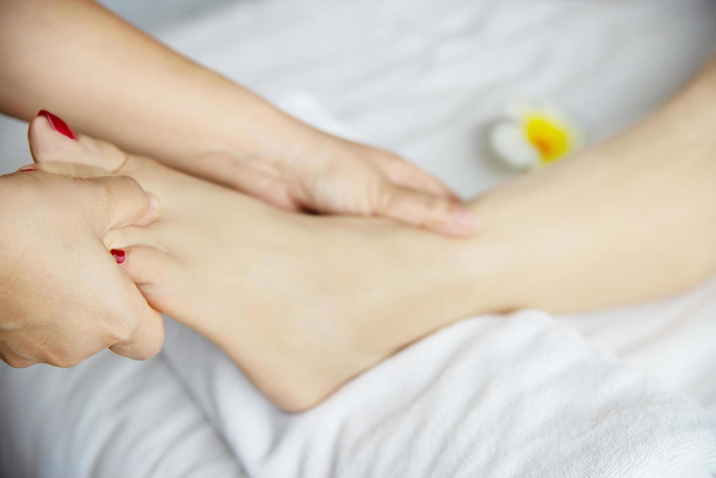 Woman receiving foot massage service from masseuse close up at hand and foot - relax in foot massage therapy service concept photo