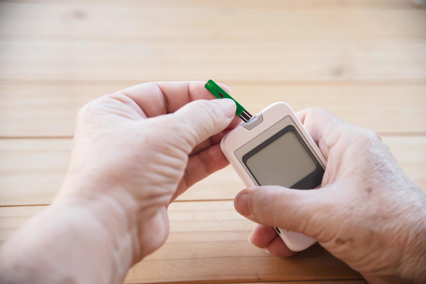 Old lady is testing blood sugar level using blood sugar test kid set - people with medical equipment concept photo