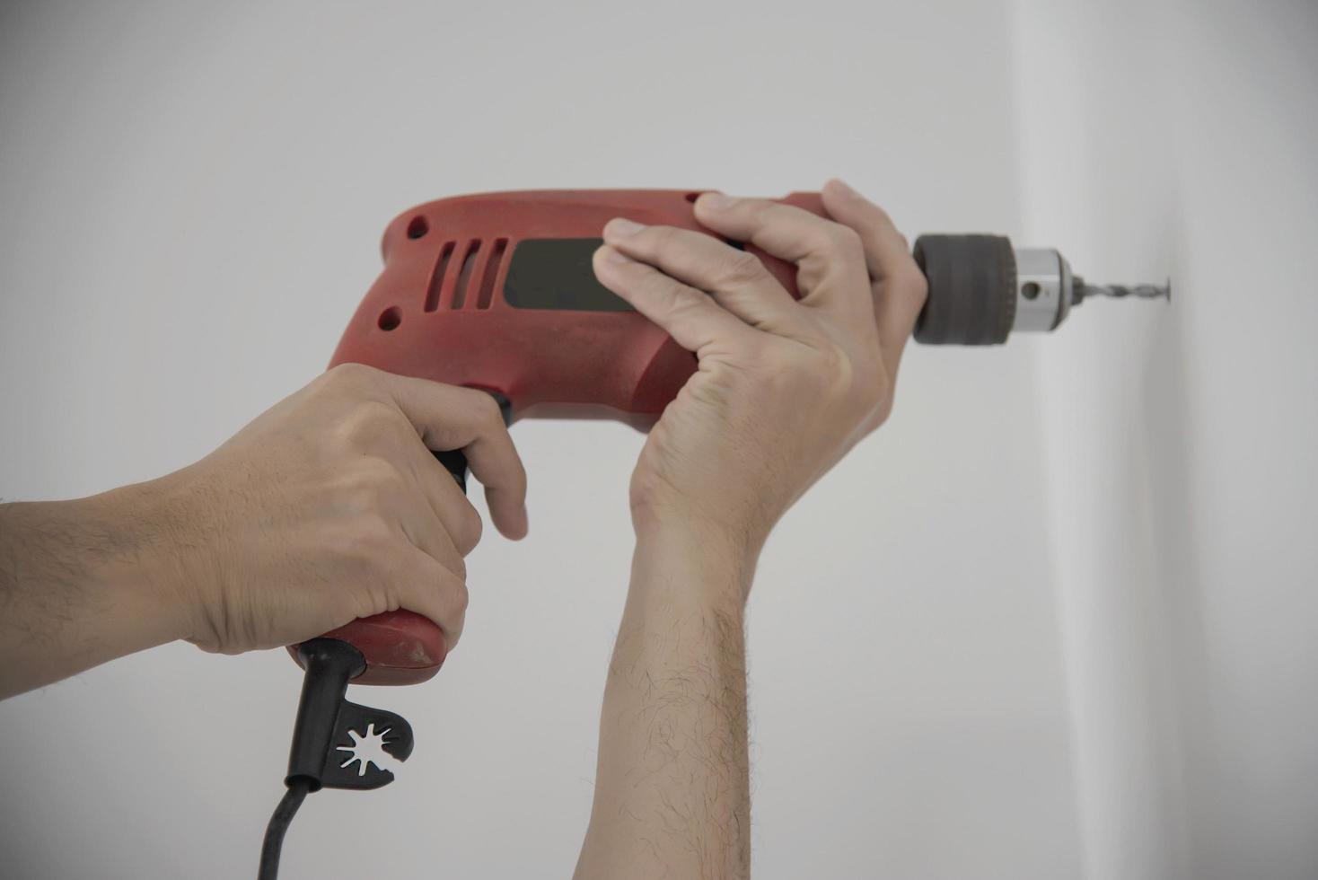 Man using hand drill device for installing home furniture at new white wall - people DIY home furniture installation concept photo