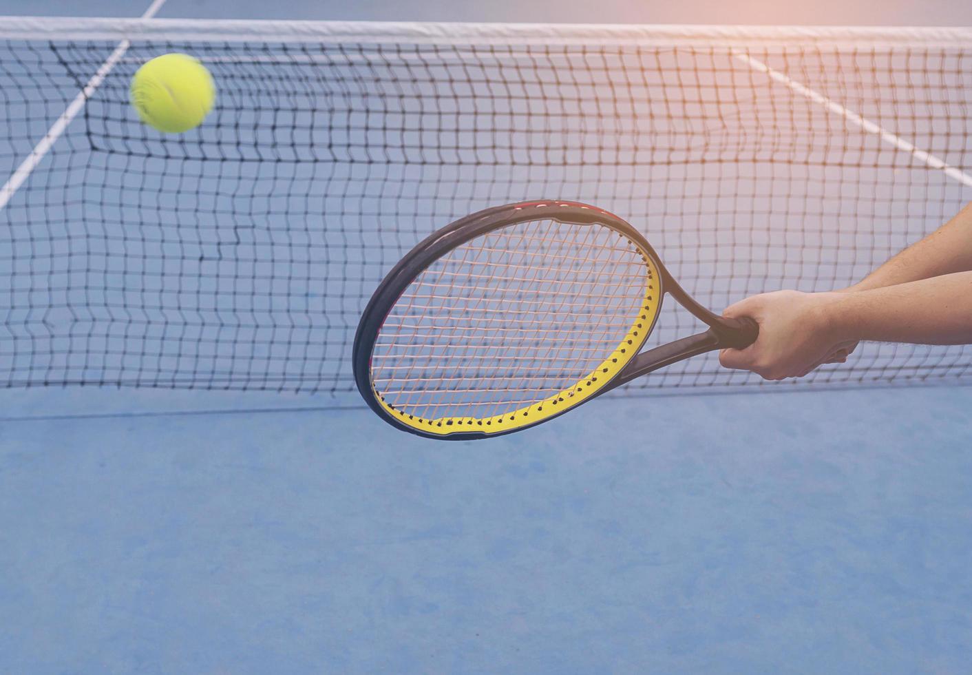 hombre que sostiene la raqueta a punto de golpear una pelota en la cancha de tenis foto