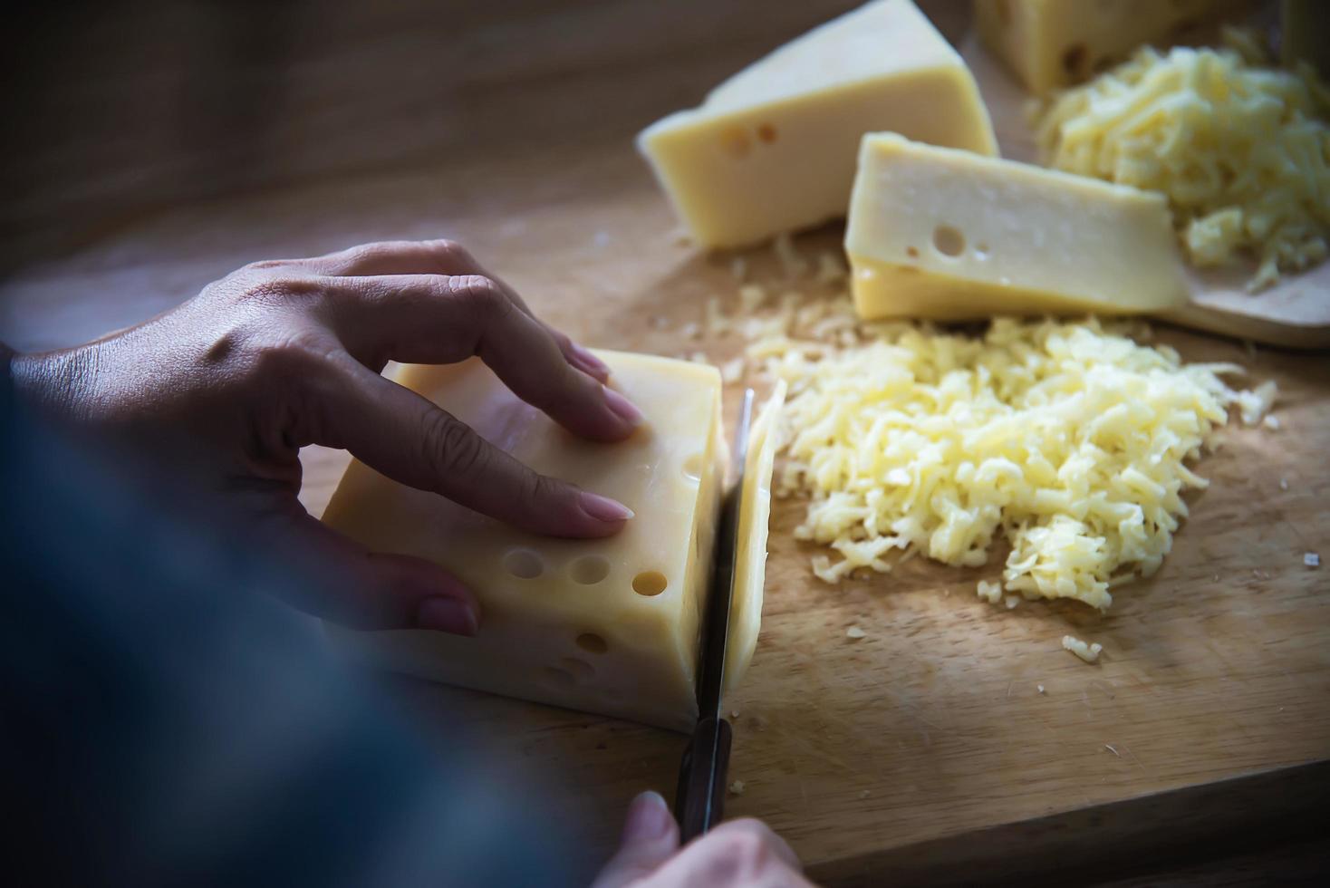 Woman preparing cheese for cook using cheese grater in the kitchen - people making food with cheese concept photo